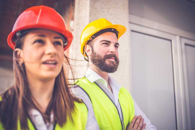 Two construction workers is looking at something.